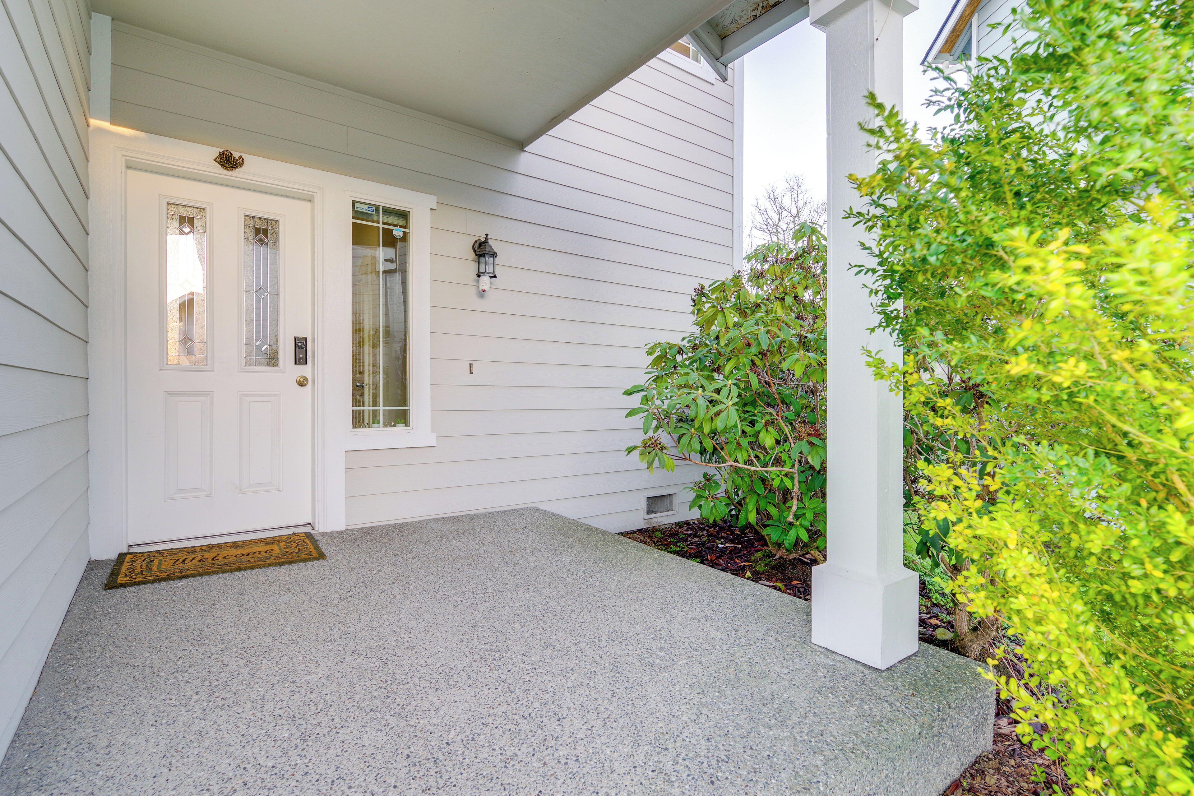 A house entrance with a white door, a doormat, and a small porch area.
