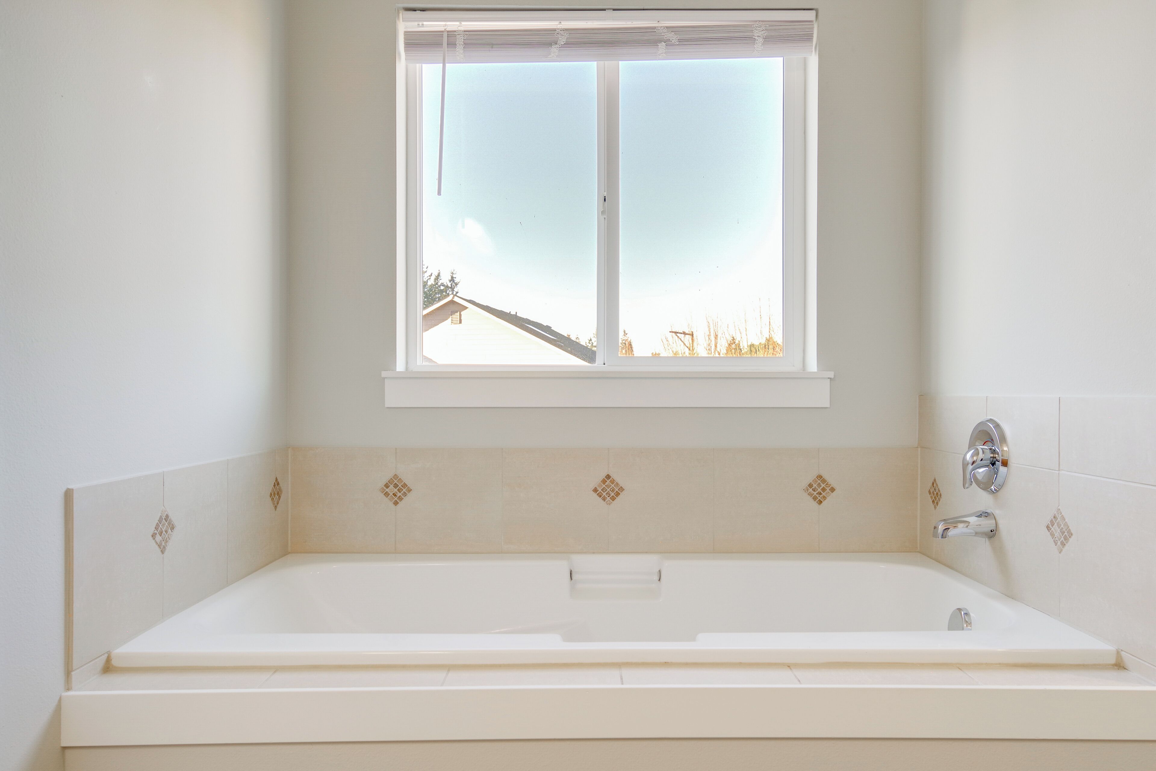 A bathroom with a bathtub, a window, and a shower area.