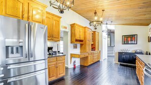 Una cucina spaziosa con mobili in legno, elettrodomestici in acciaio inossidabile e soffitto in legno.