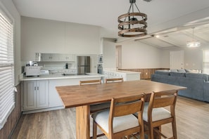 A modern kitchen with white cabinets, a wooden dining table, and a gray sofa in the living area. - Pond View, Fishing, Bbq, Fireplace, and More (Douglas)