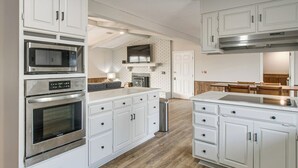 A modern kitchen with white cabinetry, stainless steel appliances, a brick accent wall, and a dining area with wooden chairs. - Pond View, Fishing, Bbq, Fireplace, and More (Douglas)