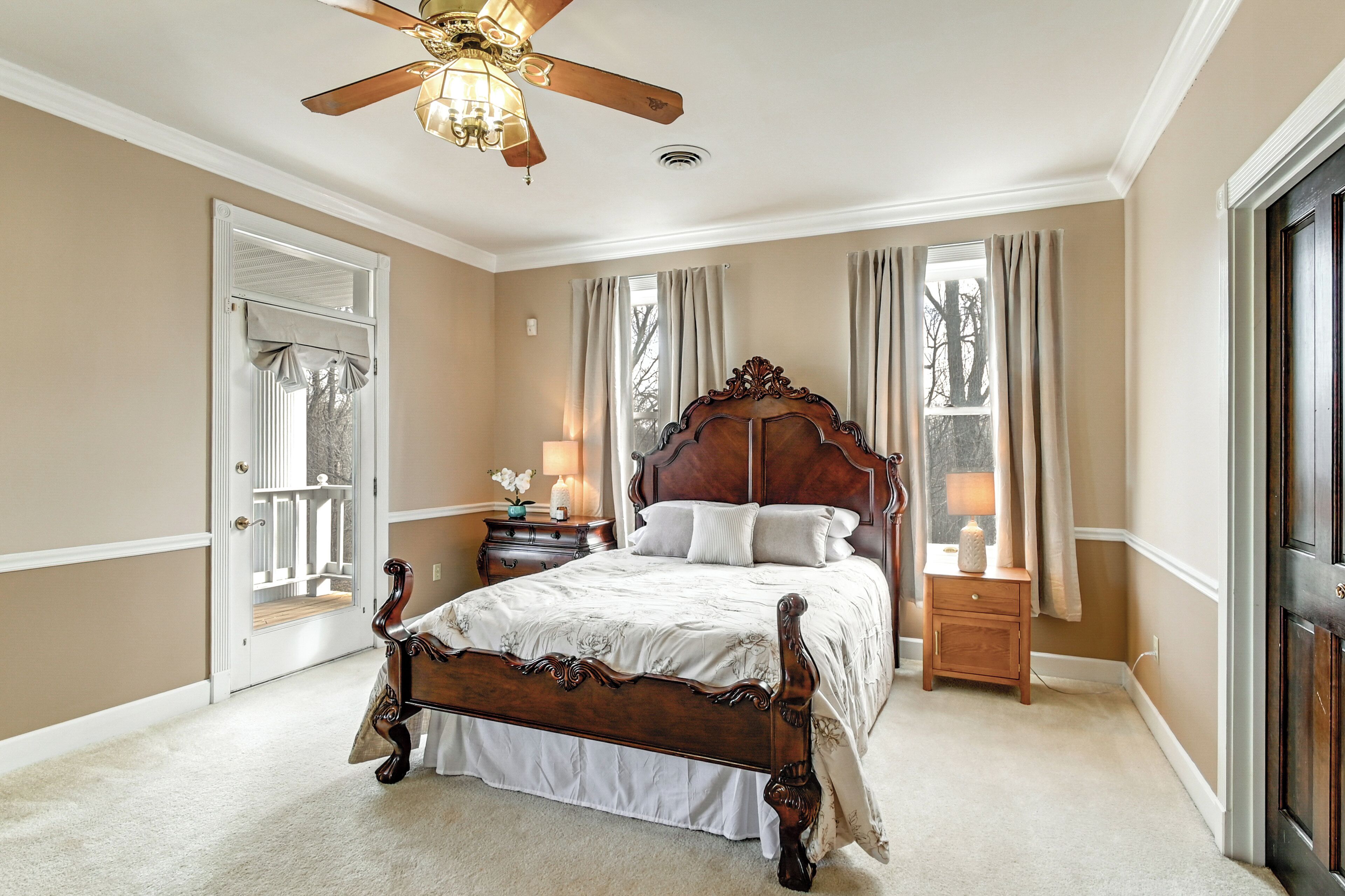 A bedroom with a large bed, a ceiling fan, and two bedside tables with lamps.