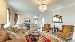 A spacious living room with a large red carpet, a chandelier, and multiple seating options including sofas and armchairs. - Spacious Shawnee Forest Hideaway! Hilltop Estate (Gorham)