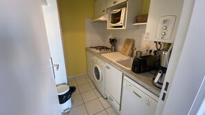 A compact kitchen with a washing machine, a toaster, and a microwave. - Charming 1-Bedroom with Balcony, Parking Included, Close to Beach & Shops (Arcachon)