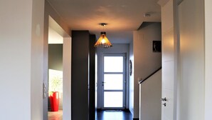 En gang med moderne design, inklusive en lampe, en dør med et vindue og en trappe.