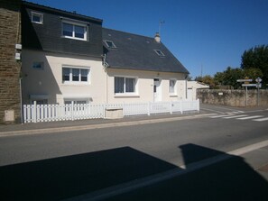 Ein zweistöckiges Haus mit weißer Fassade, schwarzem Dach und weißem Zaun.