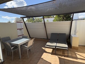 A patio with a table and chairs, a sun lounger, and a shaded area. - Air-conditioned villa with parking for 2 people in Cap d'Agde (Cap d'Agde)