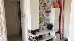 A living room with a white entertainment unit against a wall with a leaf pattern wallpaper. - Charming T2 in Saint-Palais-sur-Mer, near Nauzan beach, private box (Saint-Palais-sur-Mer)