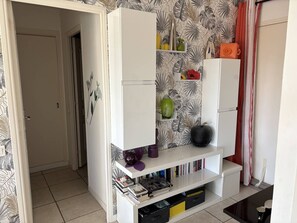 A living room with a white entertainment unit against a wall with a leaf pattern wallpaper. - Charming T2 in Saint-Palais-sur-Mer, near Nauzan beach, private box (Saint-Palais-sur-Mer)