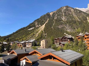 A mountain resort with chalet-style buildings, a clear sky, and a prominent mountain in the background. - Modern apartment near center and cable car (Pralognan-la-Vanoise)