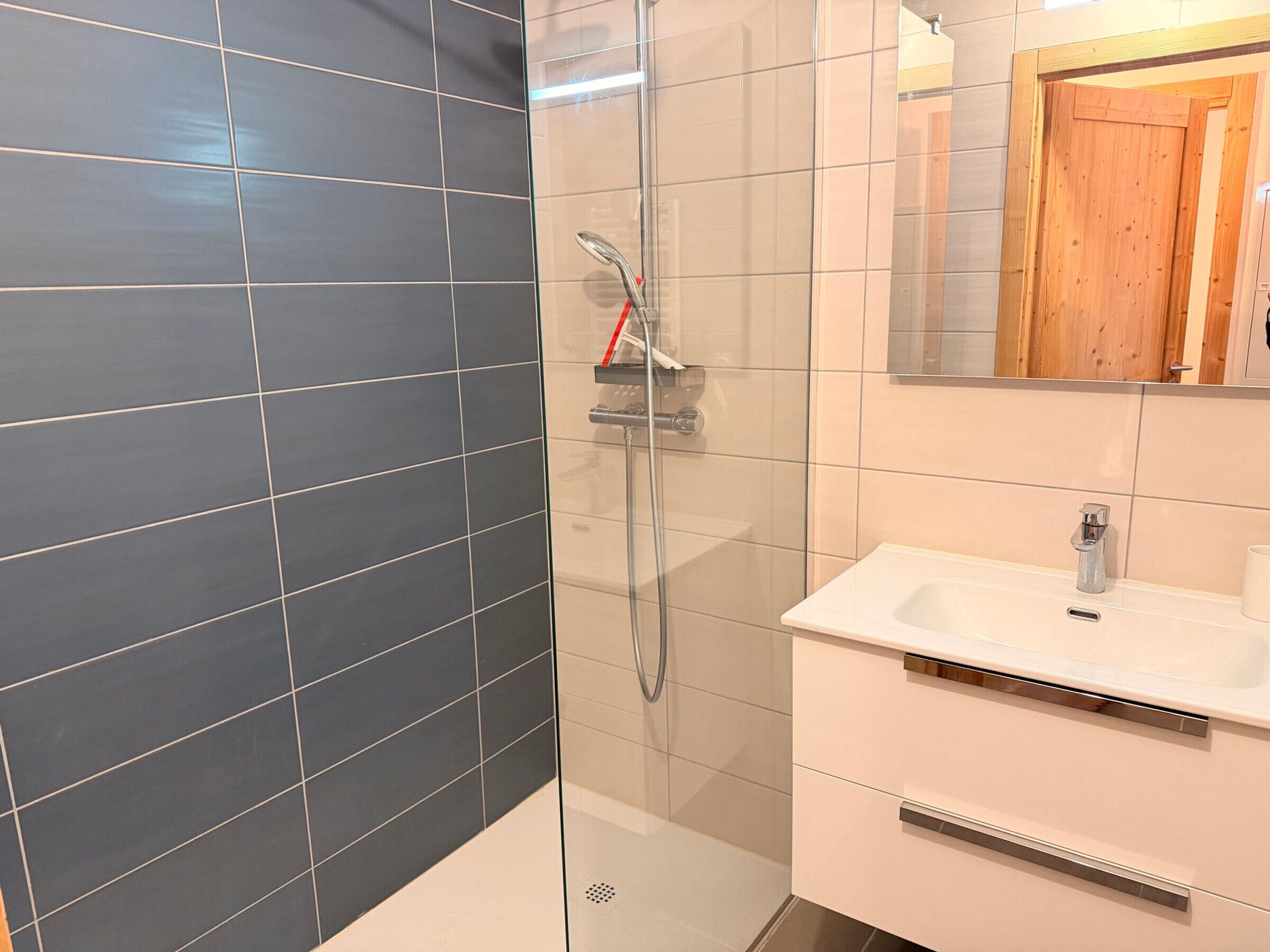 Un bagno con doccia, lavandino e specchio.