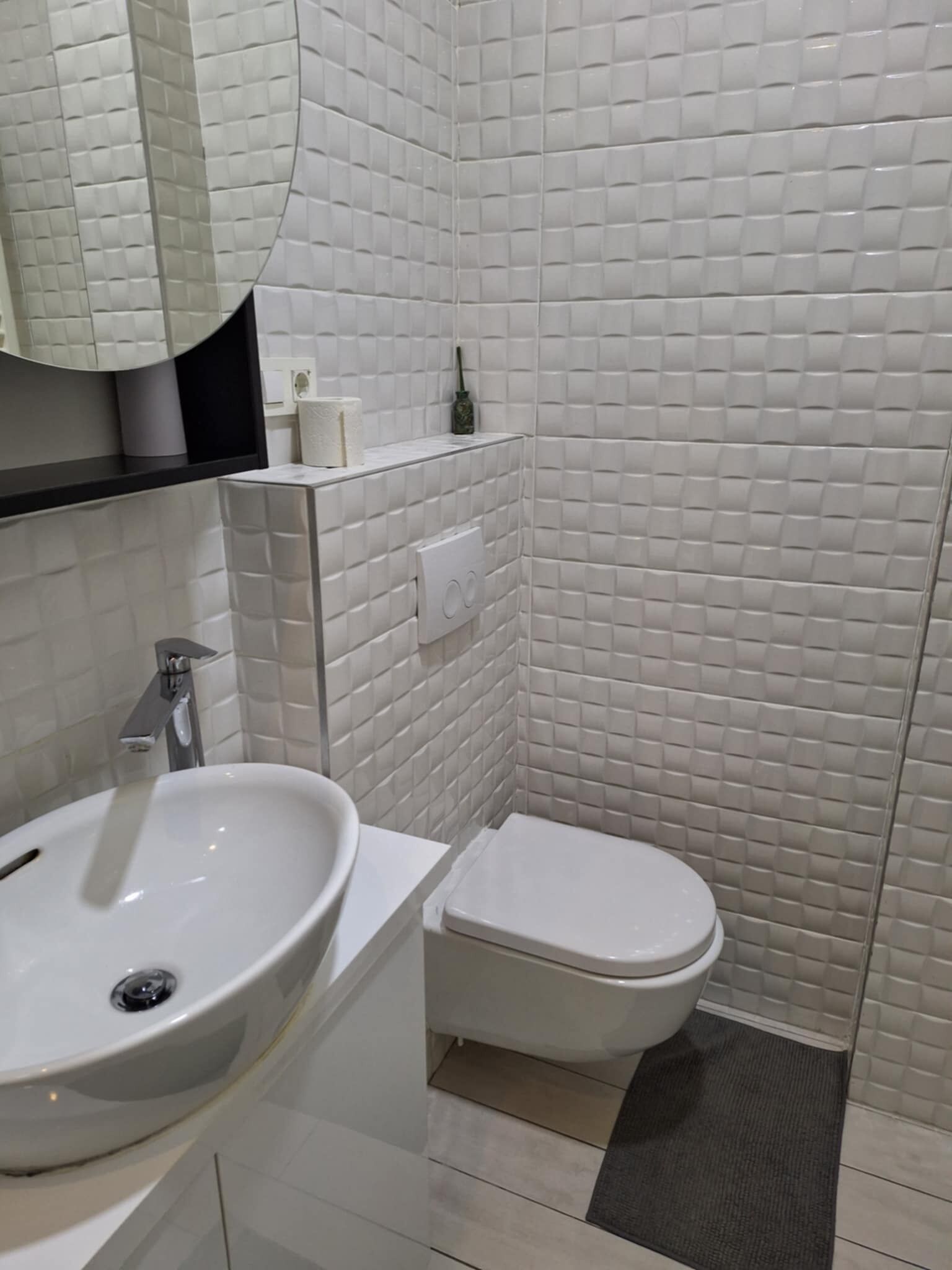 Een badkamer met een wit wastafel, toilet en een spiegel boven het wastafel.