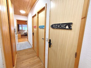 A hallway with wooden doors, each labeled with a destination sign. - Charming 2-room apartment in Méribel, 4 people, near slopes (Méribel)