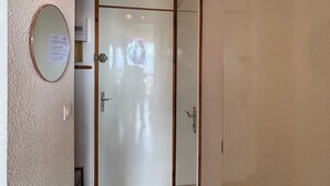 A room with a white door, a small mirror, and a wall-mounted light fixture. - Studio for 4 in Vallandry, terrace and near slopes (Peisey-Vallandry)