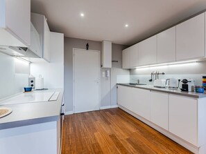 A modern kitchen with white cabinets, a wooden floor, and a stainless steel sink. - Arcachon Pereire: 1-Bed Apt Beachfront with Balcony and Parking (Arcachon)