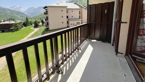 Een balkon met uitzicht op een berg en een gebouw op de achtergrond.