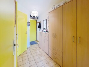A hallway with a yellow door, a wooden wardrobe, and a tiled floor. - Cozy retreat in Valloire - 4 pers, pets welcome (Valloire)