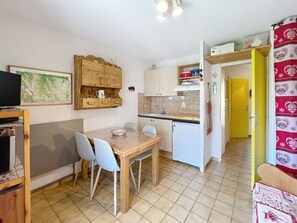 A compact kitchen with a dining area, wooden cabinets, and a tiled floor. - Cozy retreat in Valloire - 4 pers, pets welcome (Valloire)