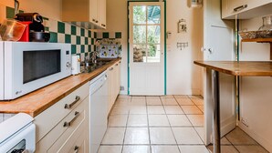 A compact kitchen with white cabinets, a microwave, a sink, and a window with a view of greenery. - ARCACHON, LES ABATILLES : A 450 M DE LA CELEBRE SOURCE DES ABATILLES ! (Arcachon)