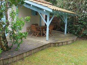 Zona de terrassa coberta amb taula i cadires, envoltada per un mur de pedra i vegetació.