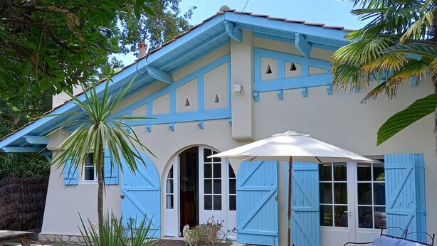 A house with blue shutters and a covered patio area with a table and chairs. - ARCACHON, LES ABATILLES : A 450 M DE LA CELEBRE SOURCE DES ABATILLES ! (Arcachon)