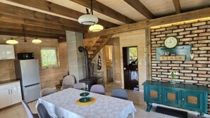 A rustic wooden interior with a dining table, chairs, a kitchen area, and a brick wall with a clock. - Large Holiday Home, Salt Cave, Sauna, Jacuzzi (Lipusz)