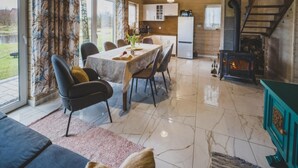 A dining area with a table set for four, surrounded by chairs, and a kitchen area with a refrigerator and stove. - Large Holiday Home, Salt Cave, Sauna, Jacuzzi (Lipusz)