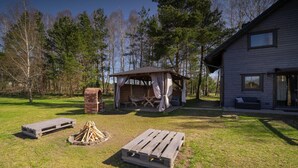 A rustic cabin with a covered outdoor seating area, a fire pit, and a wooden deck. - Large Holiday Home, Salt Cave, Sauna, Jacuzzi (Lipusz)
