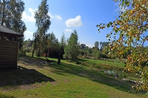 A rustic wooden cabin with a grassy yard and a small pond. - Large Holiday Home, Salt Cave, Sauna, Jacuzzi (Lipusz)