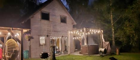 A rustic wooden house with a covered porch and string lights.