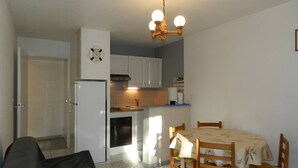 Eine kompakte Küche mit weißen Schränken, einem eingebauten Backofen und einem Essbereich mit Holztisch und Stühlen.