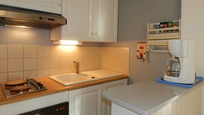 Eine Küche mit weißen Schränken, einem Spülbecken, einer Kaffeemaschine und einem Geschirrgestell.
