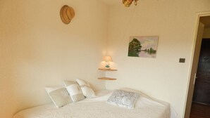 Ein Schlafzimmer mit einem großen Bett, zwei Nachttischen mit Lampen, einem Bild an der Wand und einer Tür zu einem anderen Raum.