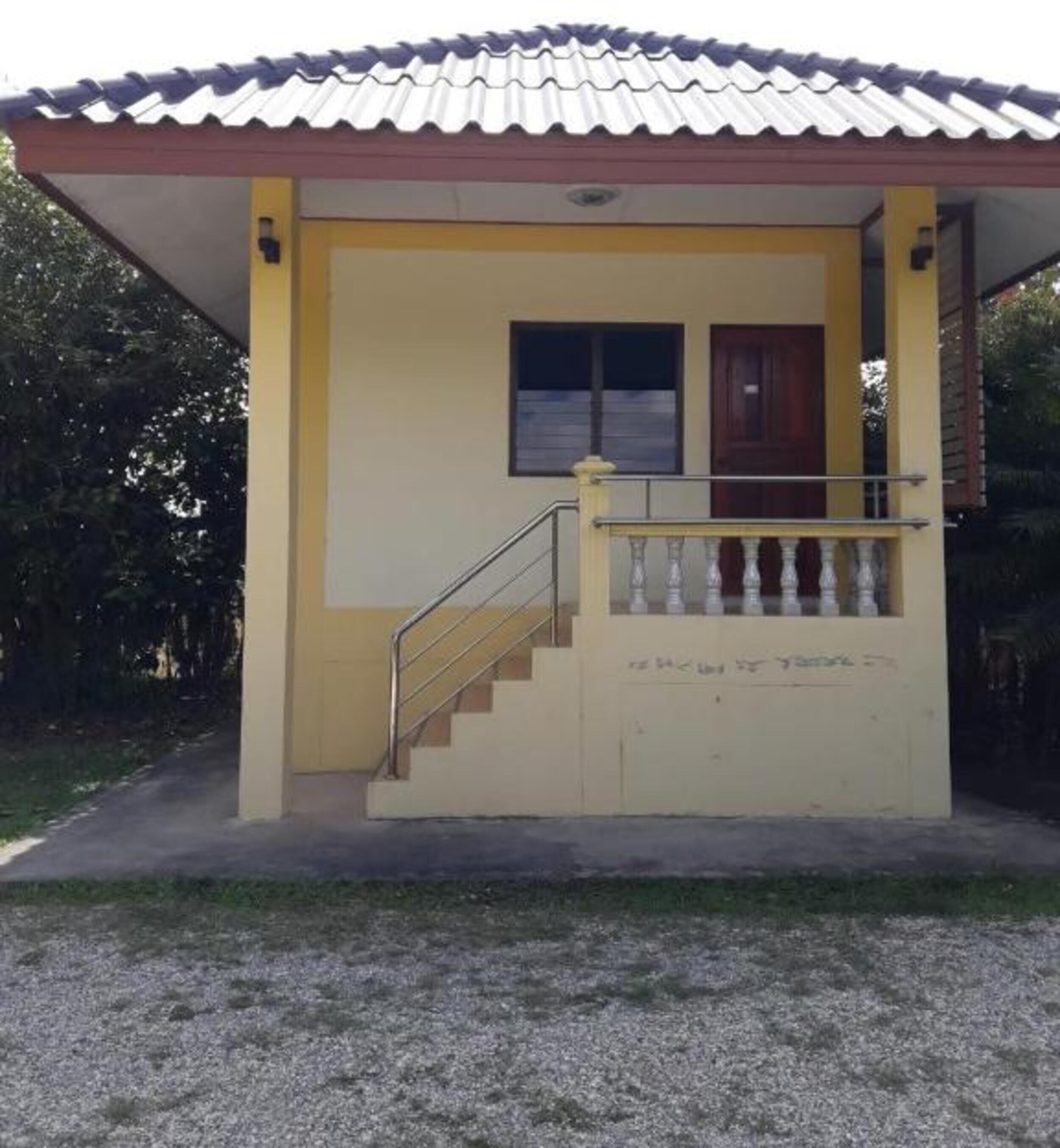 A small building with a tiled roof, a single window, and a staircase leading to a door.