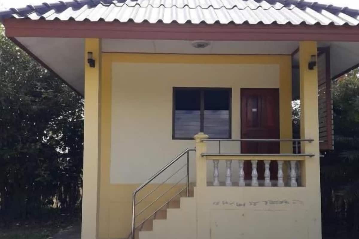 A small building with a tiled roof, a staircase leading to a door, and a window.