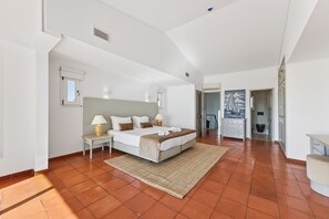 A spacious bedroom with a large bed, bedside tables, a nightstand, and a painting on the wall.