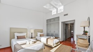 Ett hotellrum med två sängar, ett skrivbord, en stol, en lampa och en garderob.