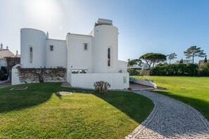 A white building with two cylindrical towers, a paved pathway, and a well-maintained lawn.
