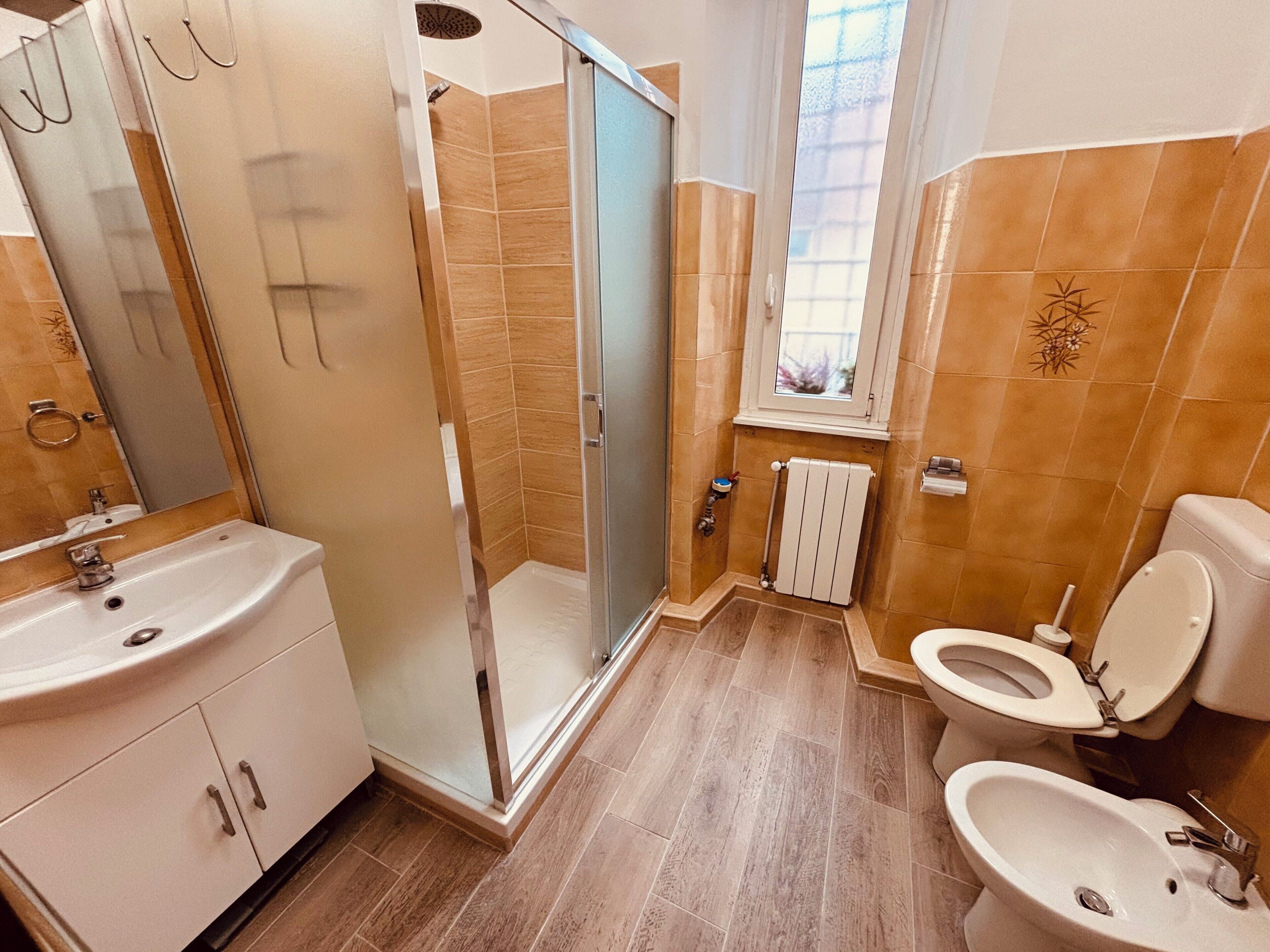 A bathroom with a shower, toilet, sink, and a window.
