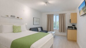 A modern hotel room with a large bed, a small sofa, a desk, and a kitchenette. - Miami Beach Escape Inviting Studio (Miami Beach)