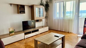 A modern living room with a wooden herringbone floor, a flat-screen TV on a wooden stand, a coffee table, and a sofa. - Adorable 1-bedroom apartment in charming Dugi Rat (Dugi Rat)