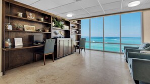 A modern office with a desk, chairs, and a large window overlooking the ocean. - 2BR Beachfront Condo with Beach Service, Pool, Gym - Sleeps 8 (Panama City Beach)