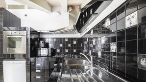 Una cucina moderna con piastrelle nere, elettrodomestici in acciaio inossidabile e lavello integrato.