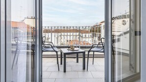 Un balcone con tavolo e sedie, vista sui palazzi e cielo sereno.