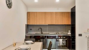 Une cuisine moderne avec des meubles en bois, un évier en acier inoxydable et un coin repas avec une table mise pour deux personnes.