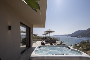 Ett modernt utomhusområde med en bubbelpool och utsikt över havet och bergen.