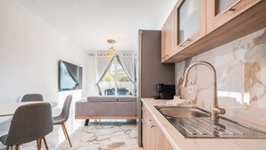 A modern kitchen with a marble countertop, stainless steel sink, and wooden cabinets. - Punta Mare Villas - Adults Only (Pigadia)