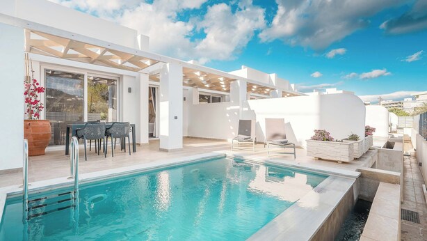 A modern outdoor pool area with a clear sky, a pergola, and a seating area with chairs and a table. - Punta Mare Villas - Adults Only (Pigadia)