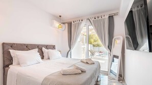 A modern bedroom with a large bed, a ceiling fan, and a view of the outdoors. - Punta Mare Villas - Adults Only (Pigadia)