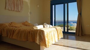 A bedroom with a bed, a view of the sea, and a balcony. - |    Rania Villas   | (Kipi Afiarti)